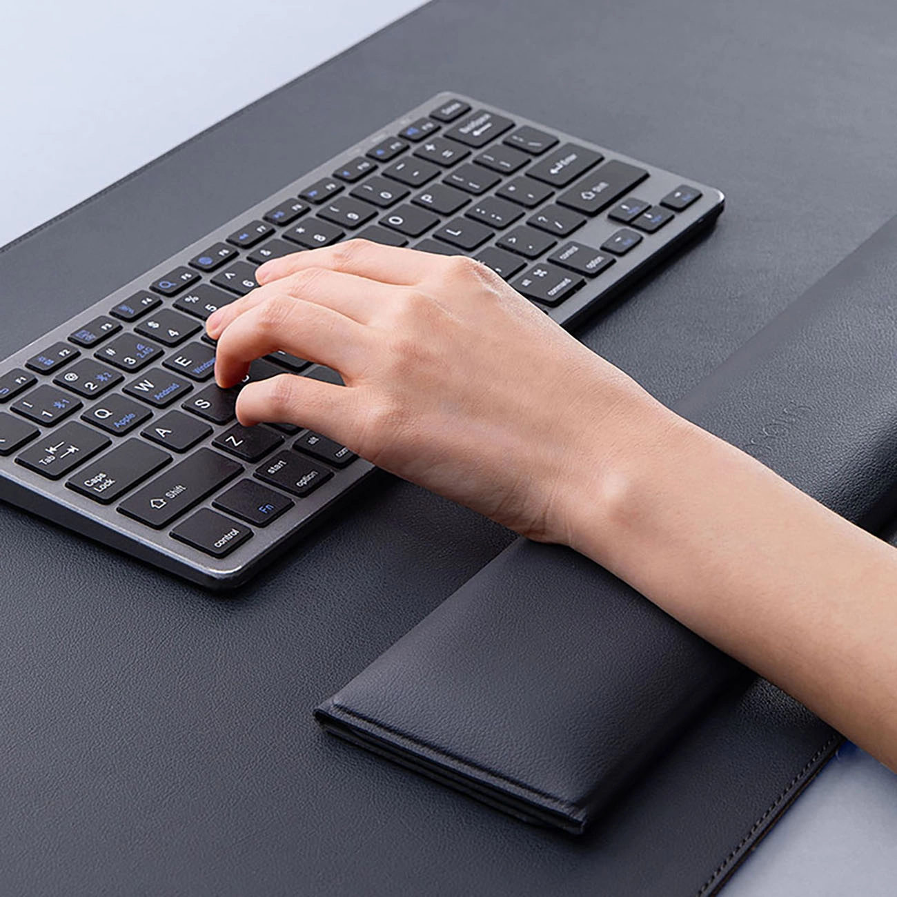 A hand typing on a keyboard on a Baseus MagPro Series II mat