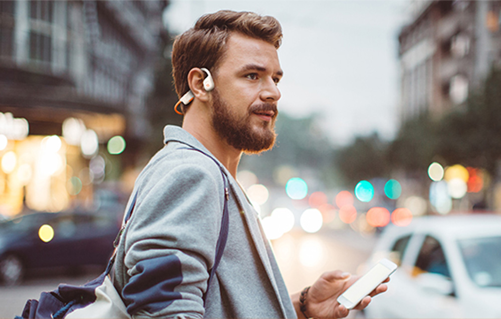 Person wearing ONIKUMA T37 headphones outdoors while holding a smartphone